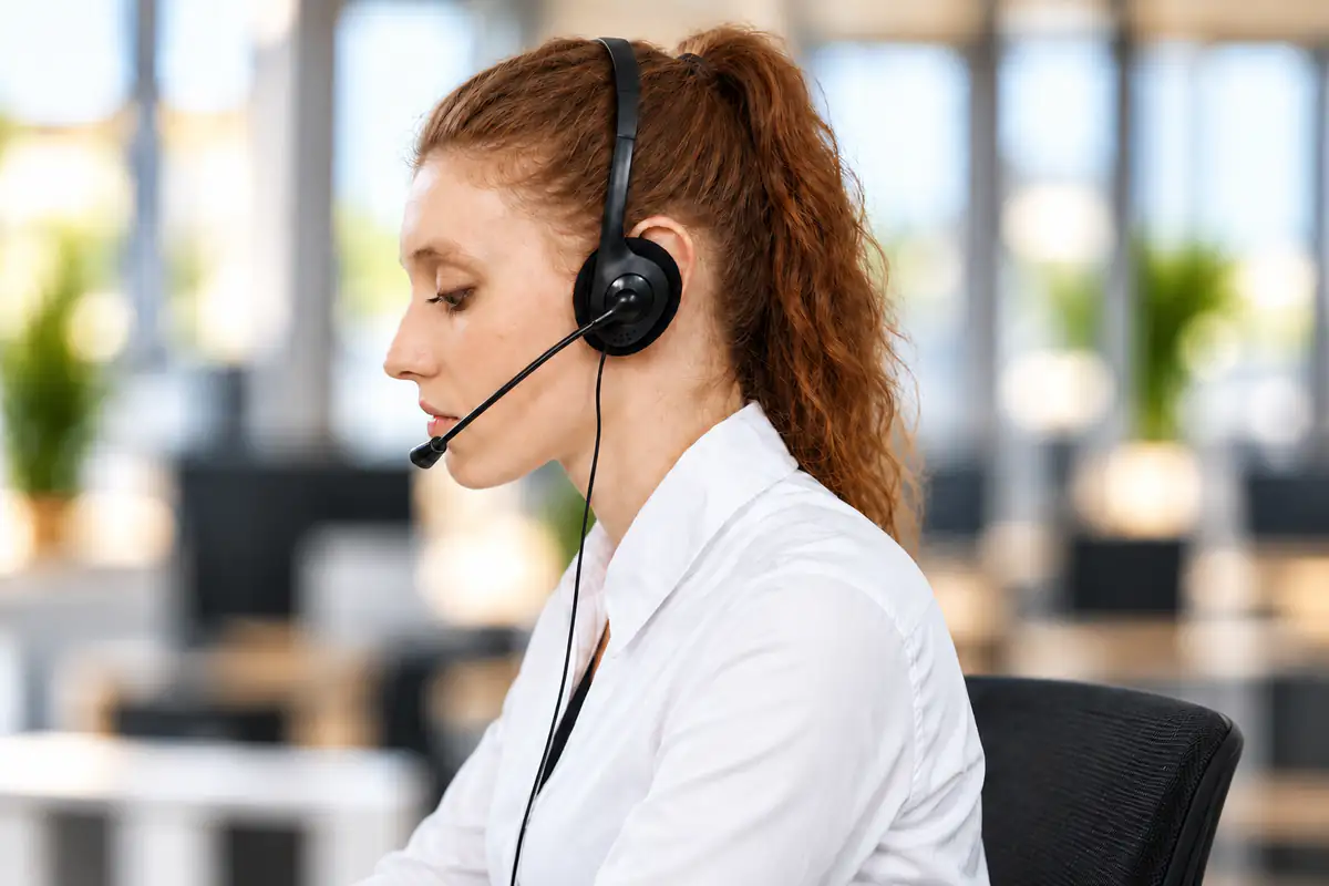 A service agent in a headset at her desk, in profile