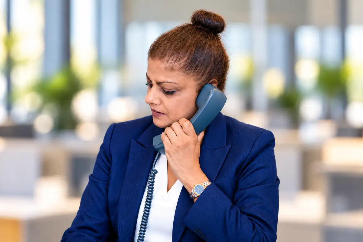 An office worker on a desk phone in a bright office
